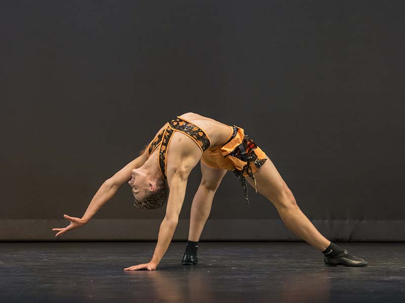 Chase Leathard dancing in costume on stage in a back bend position
