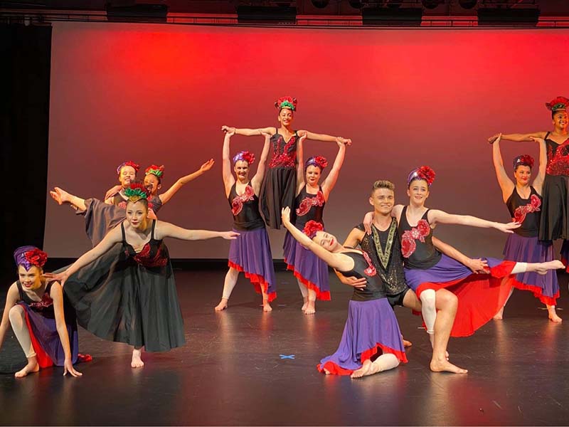 VCM Academy ballet students dancing on stage in red and purple skirts